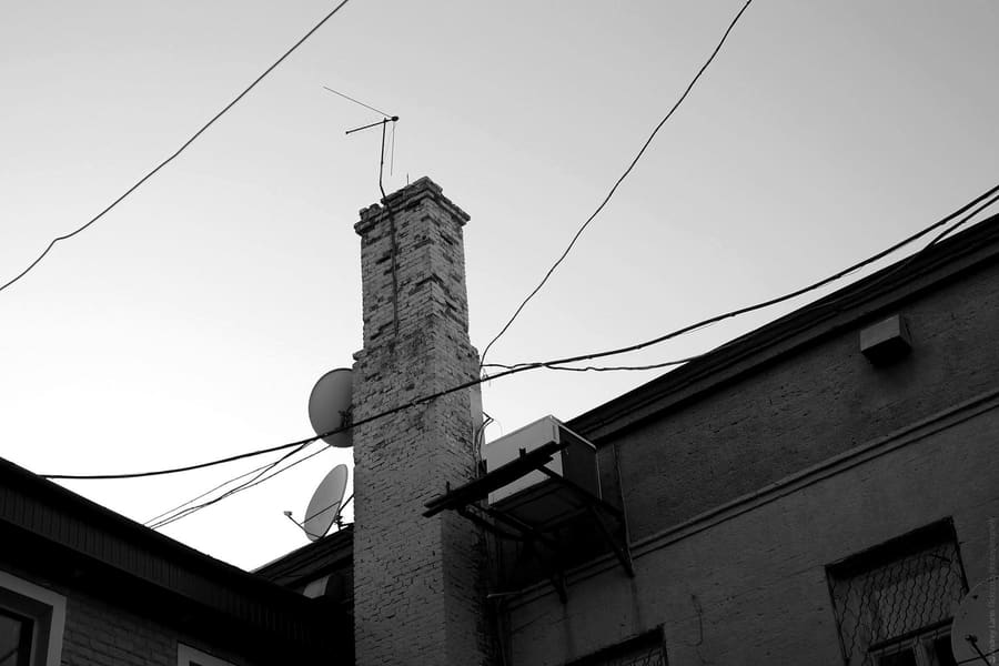 Chimney with a TV aerial, and satellite dishes on a neighbouring wall